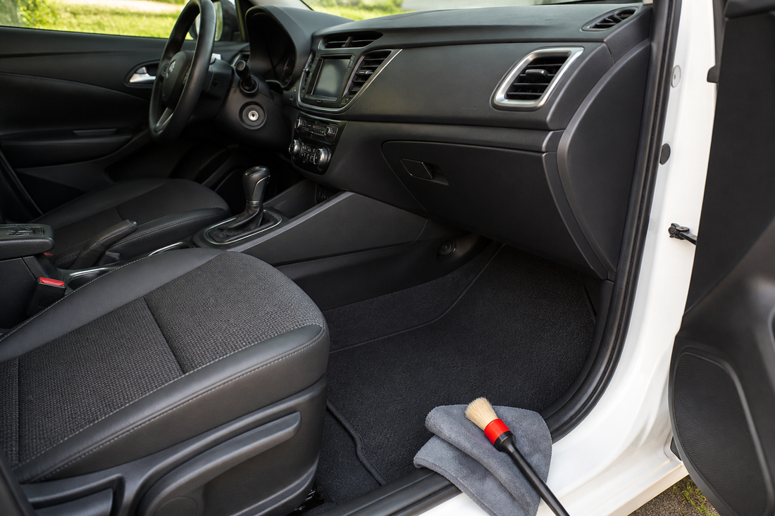 Clean car interior with the dashboard, front seats, center console, carpet, and floor mats visible